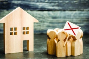 A crowd of wooden toy people protests against the rising cost of services near a wooden house. Strike against high prices. The decline in living standards, social tension and an angry mob.