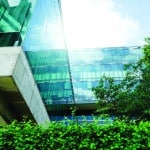 Sustainable glass office building with tree and hedge in front