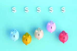 Overhead view of different-colored piggy banks racing against each other towards a line of dollar signs.